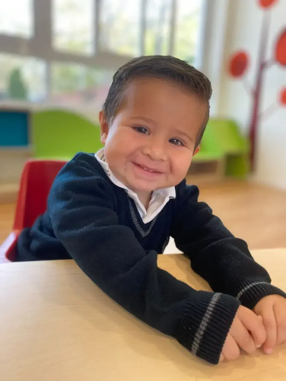Niño pequeño sonriendo en el aula durante actividades escolares en ambiente educativo